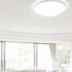 plafonnier LED de forme ronde éclairant un salon moderne et cosy aux teintes grises